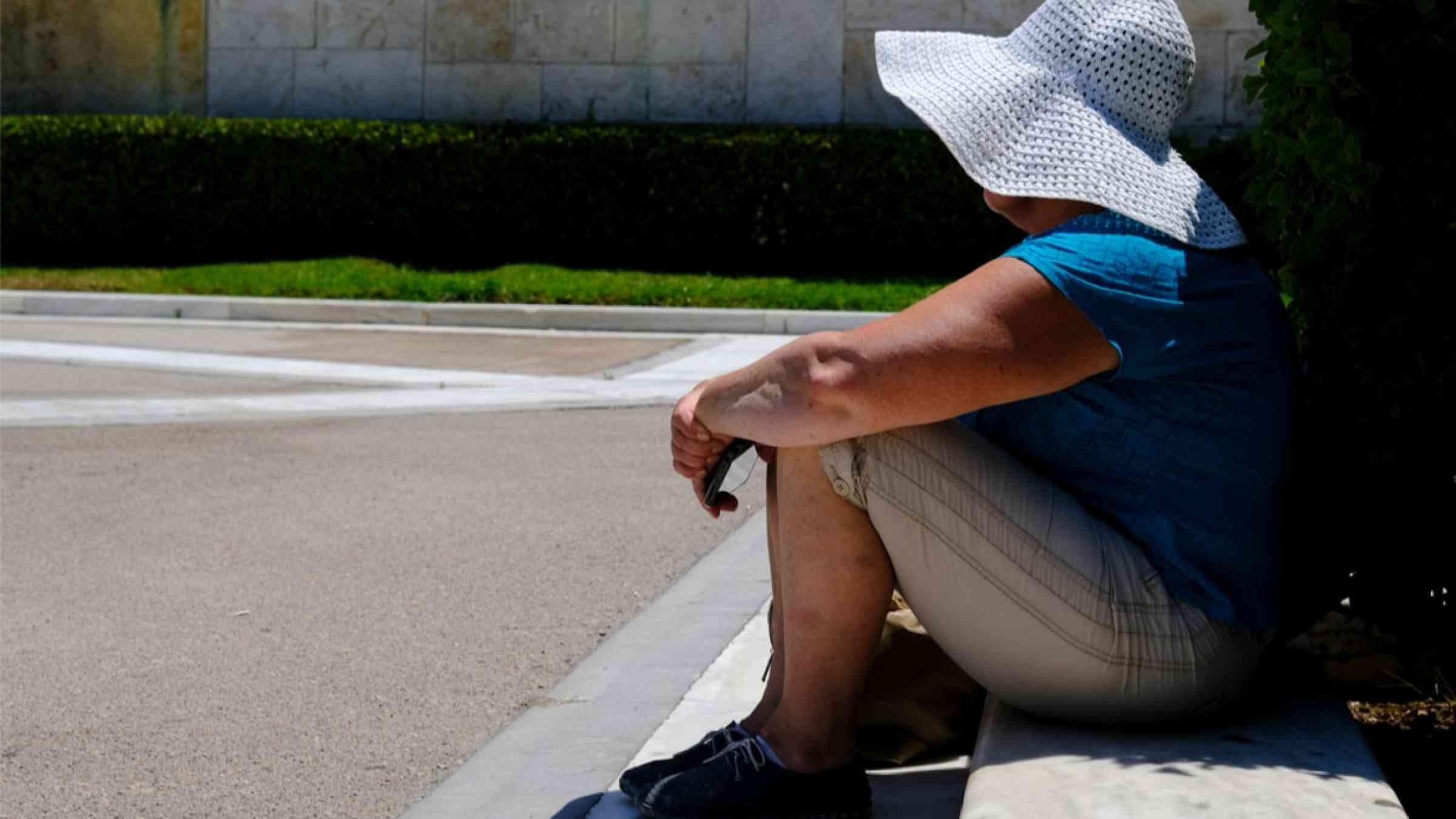 Person sitting in front of Hellenic Parliament during a hot day in Athens, 2021