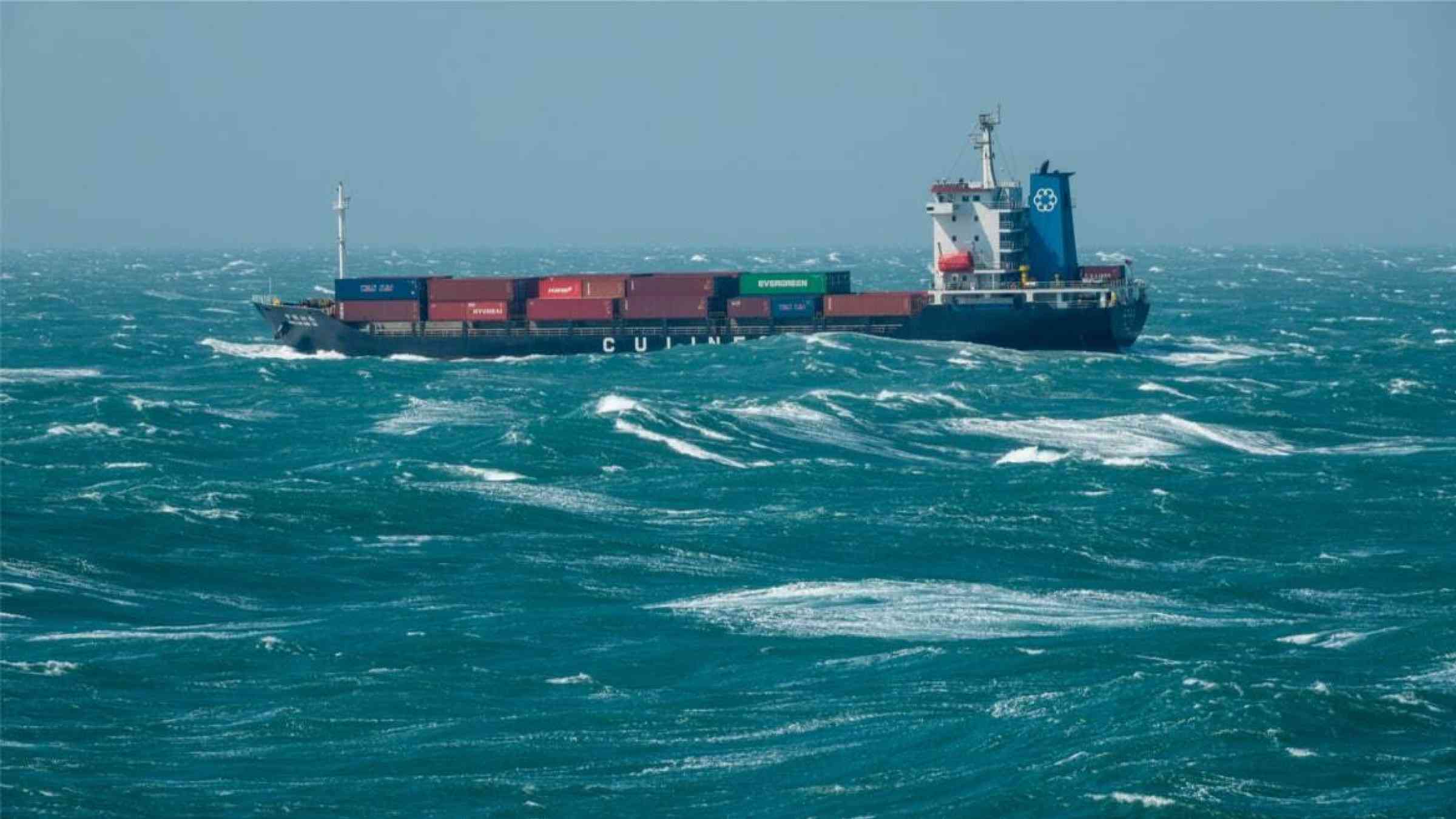 A cargo ship traverses rough seas off the coast of Shanghai
