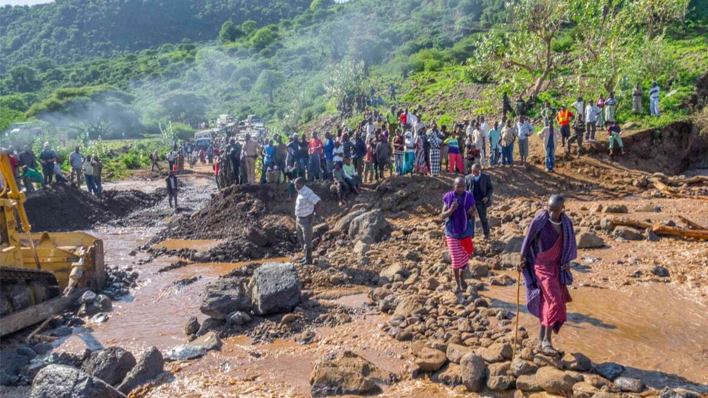 People cross a stone path across a road destroyed by mudflow in Manyara, Tanzania