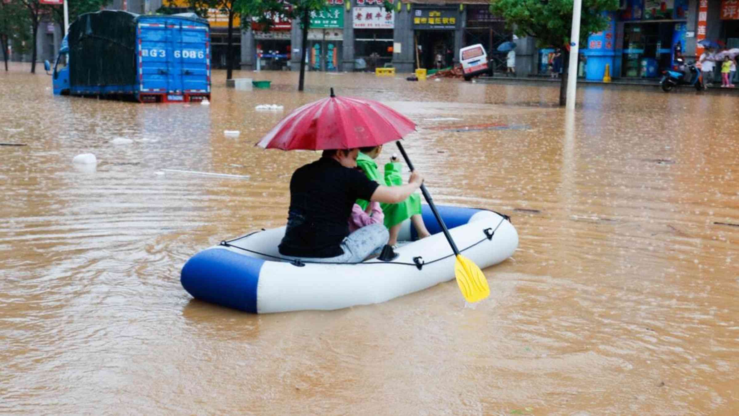 A family rows a boat through heavy floods in Jiangxi, China