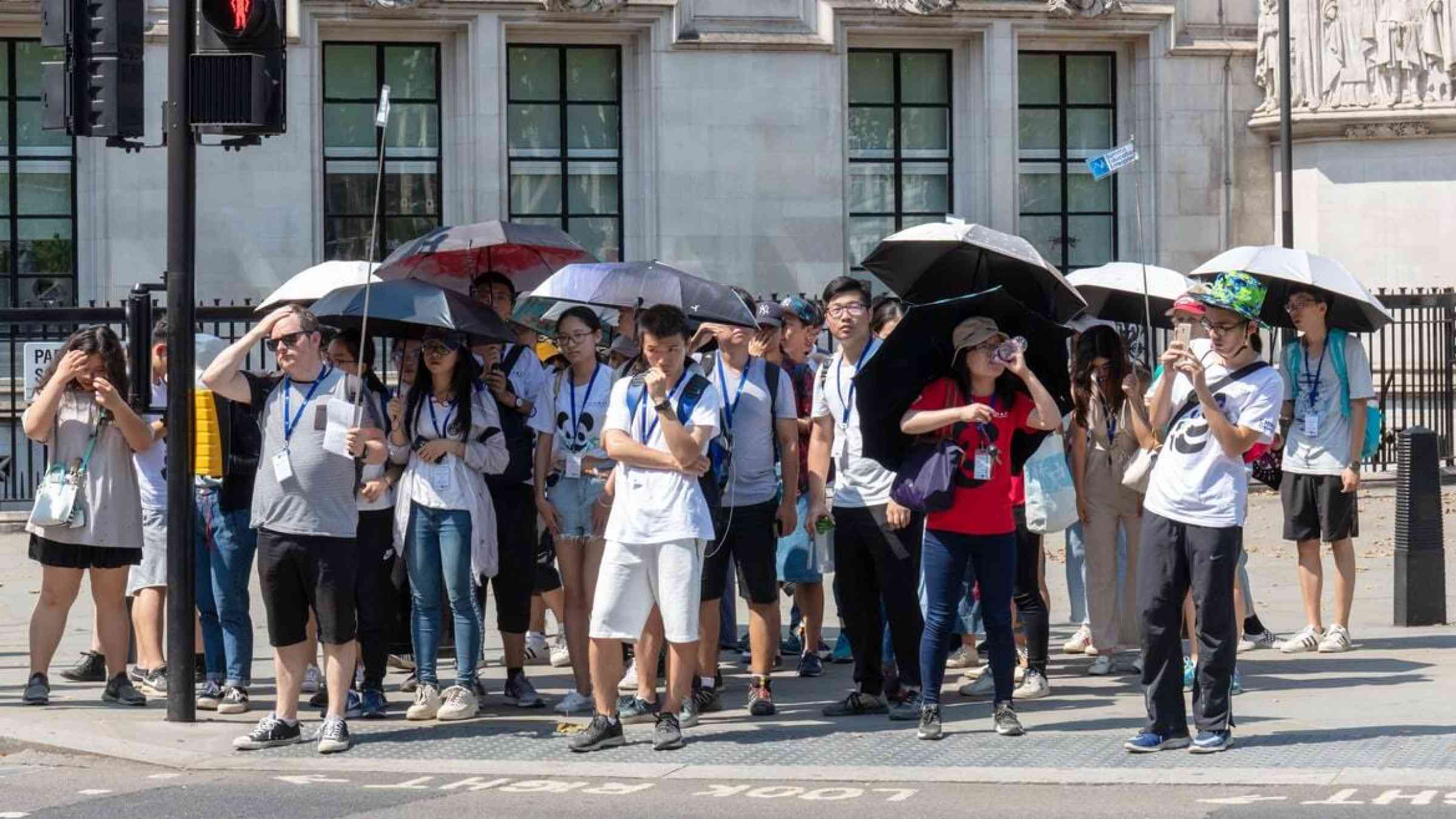 Tourists seek shade with umbrellas during a hot day in London