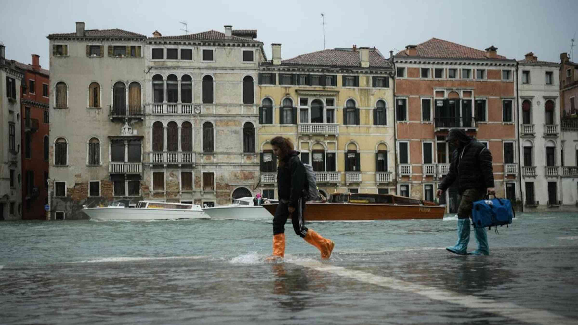 Pedestrians traverse the inundated streets of Venice, Italy