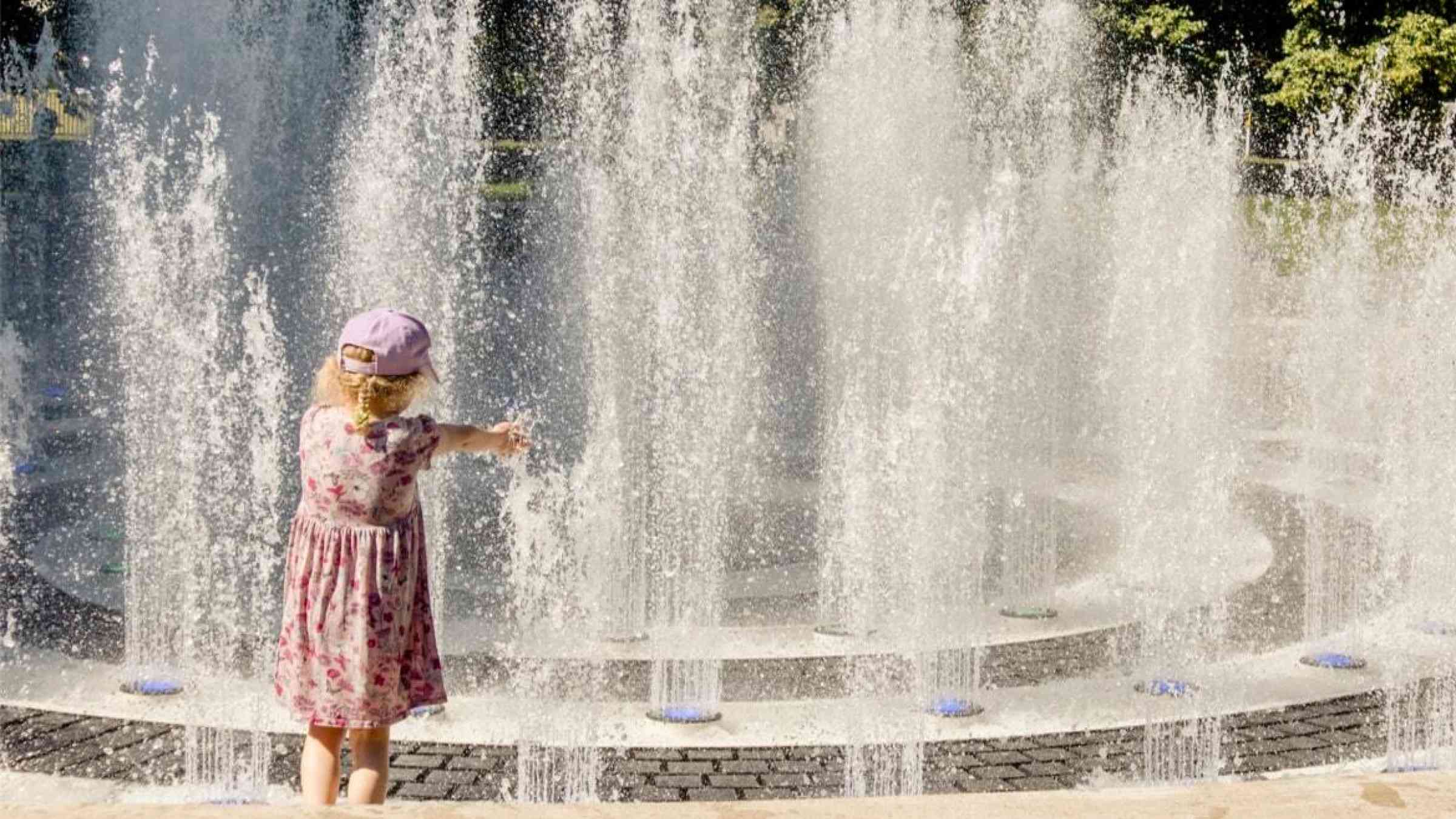 Girl playing in a fountain during a heat wave
