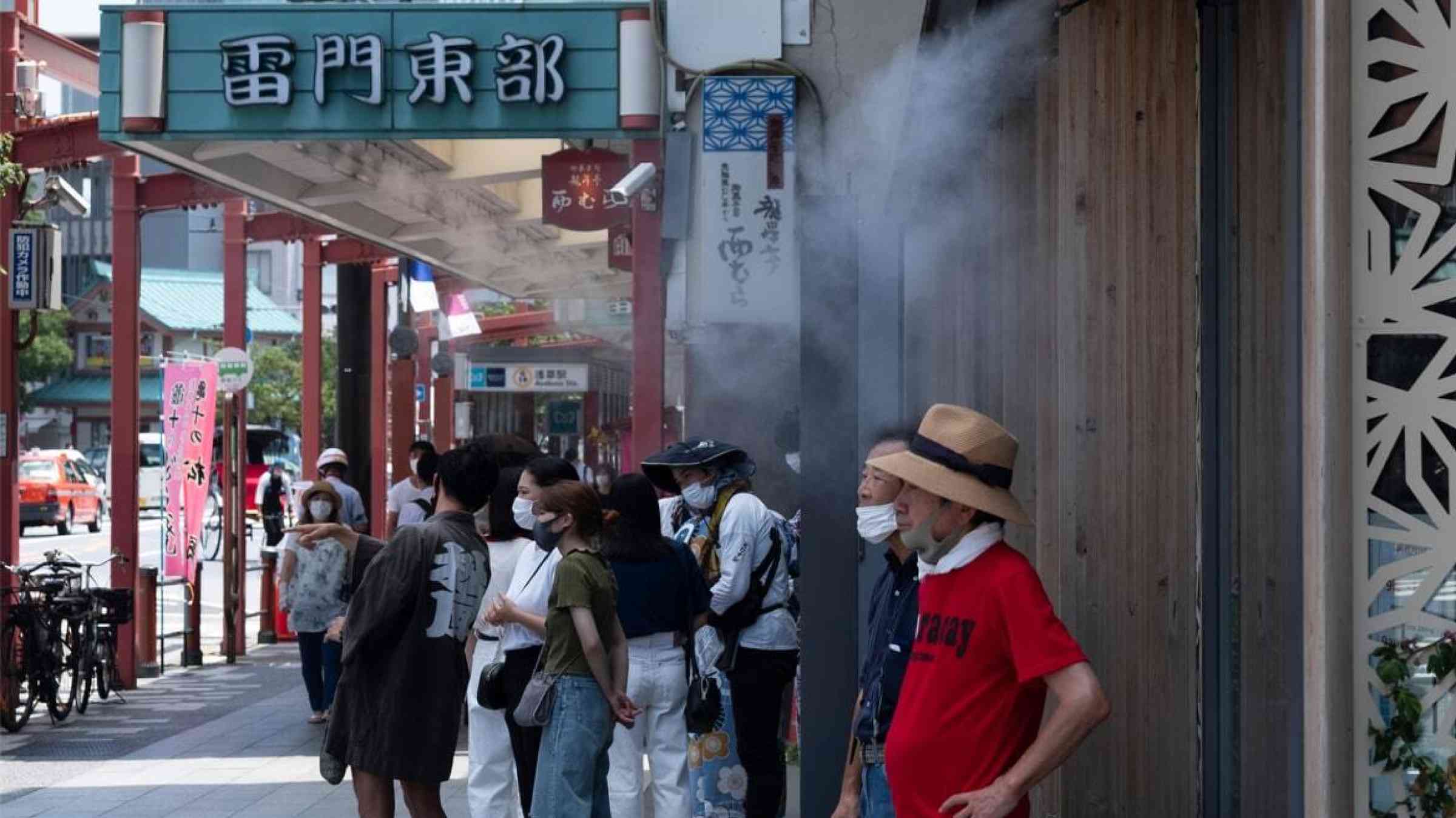 People standing under water mist sprayers in Tokyo, Japan