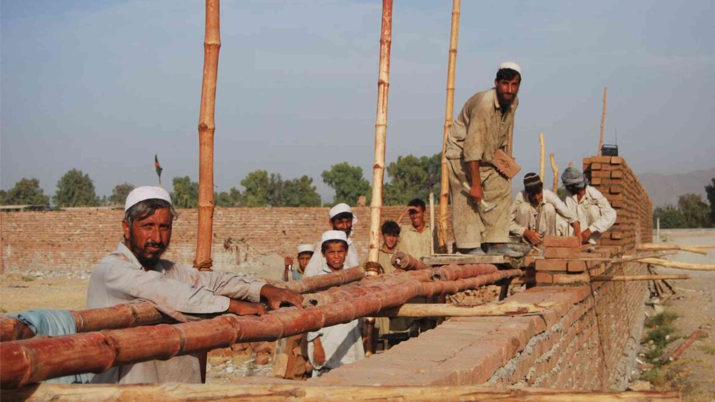 Afghan men construct a wall