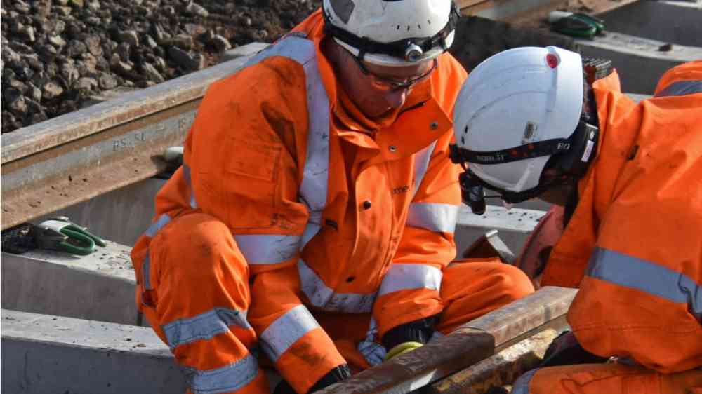 Two construction workers working on railway tracks.