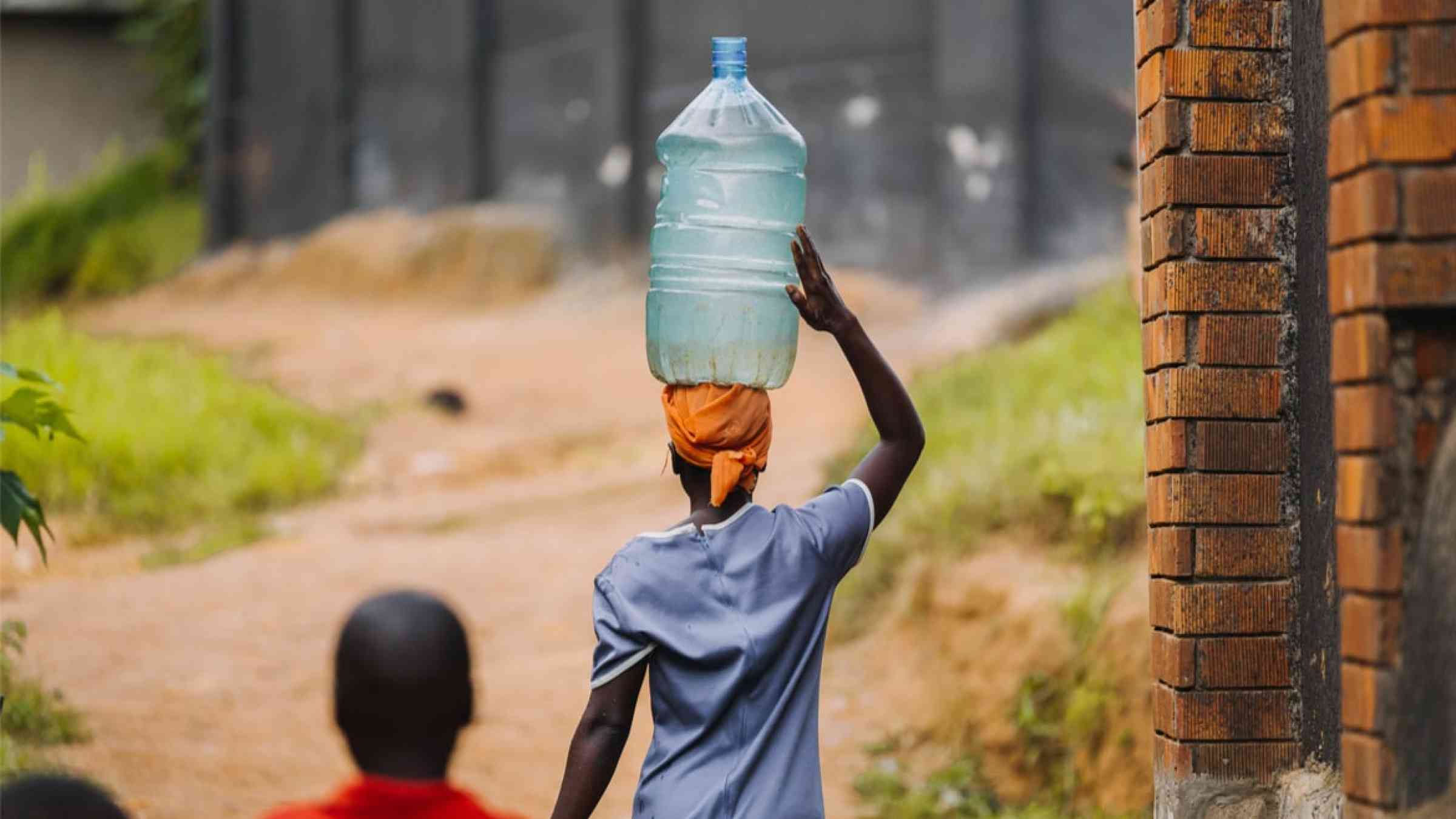 Woman carrying water can in Uganda, Africa