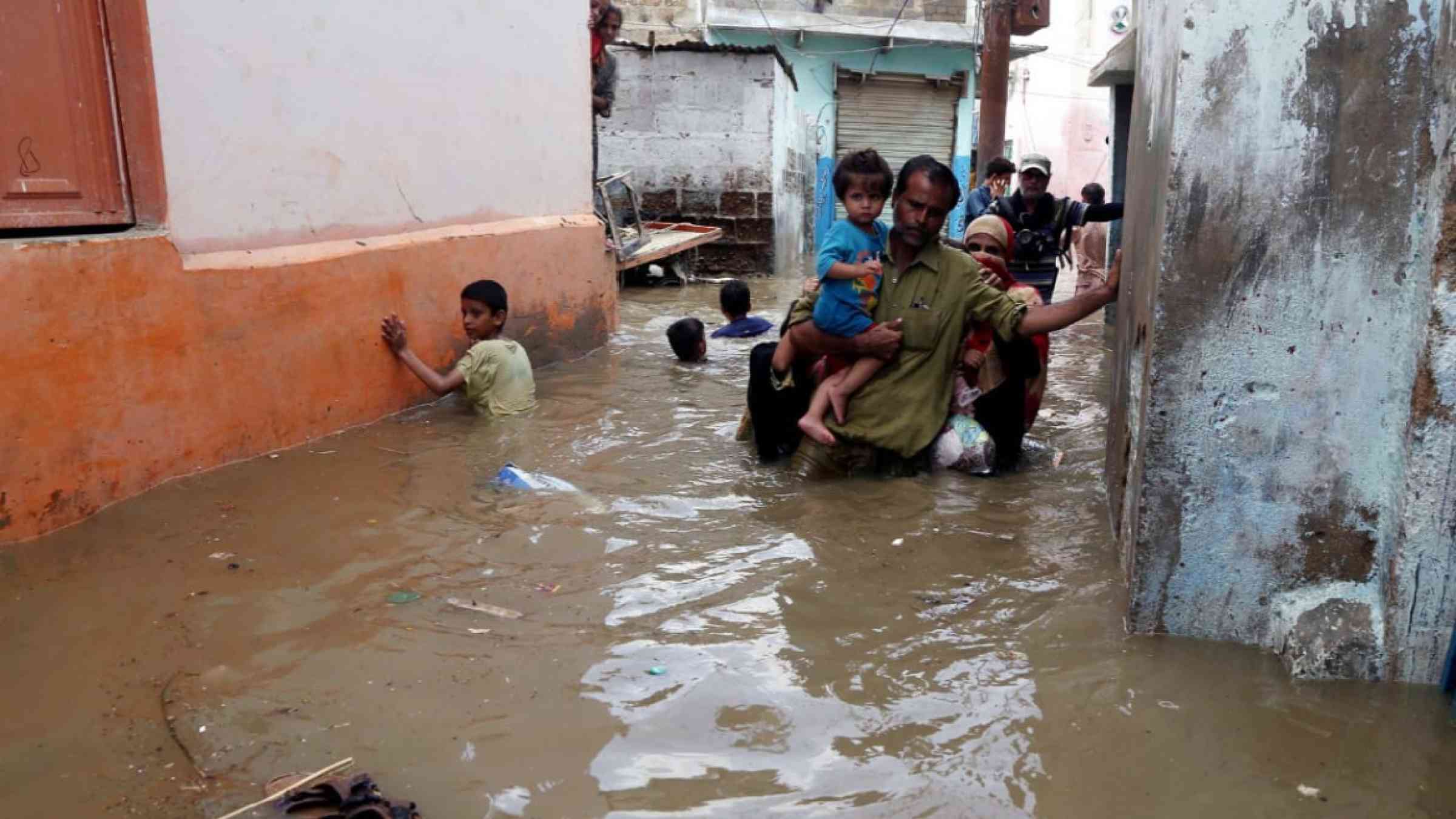 Adults and children walking through flooded streets in Pakistan