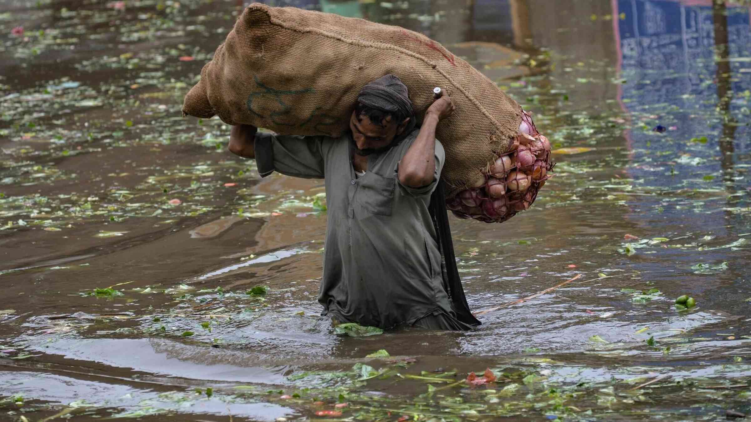 A laborer carries a sack of onions above floodwaters in Lahore, Pakistan
