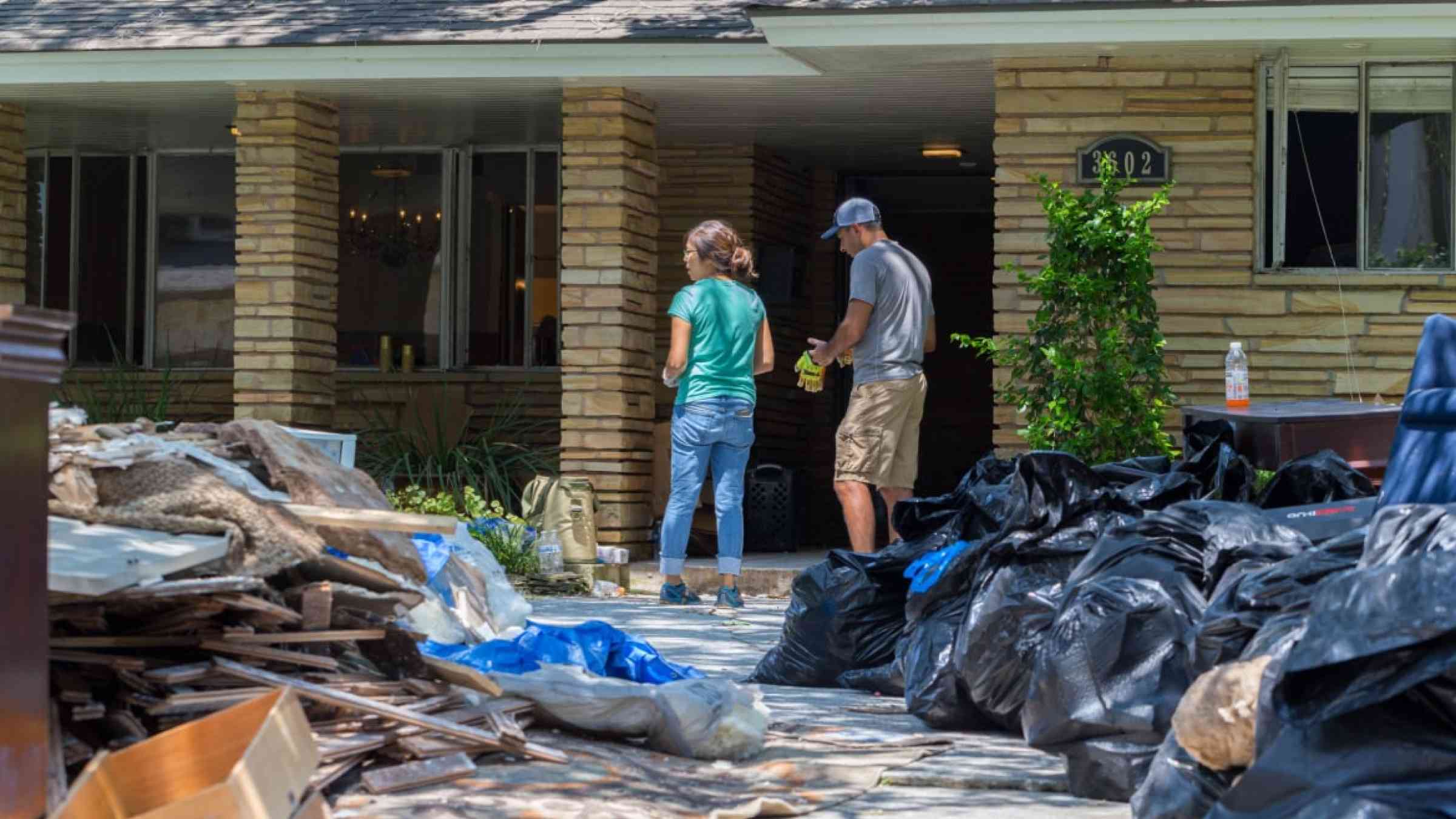 Homeowners in front of their house after floods.