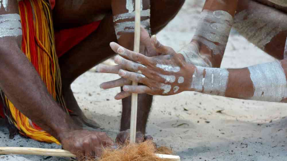 Two indigenous people demonstrating fire making craft.