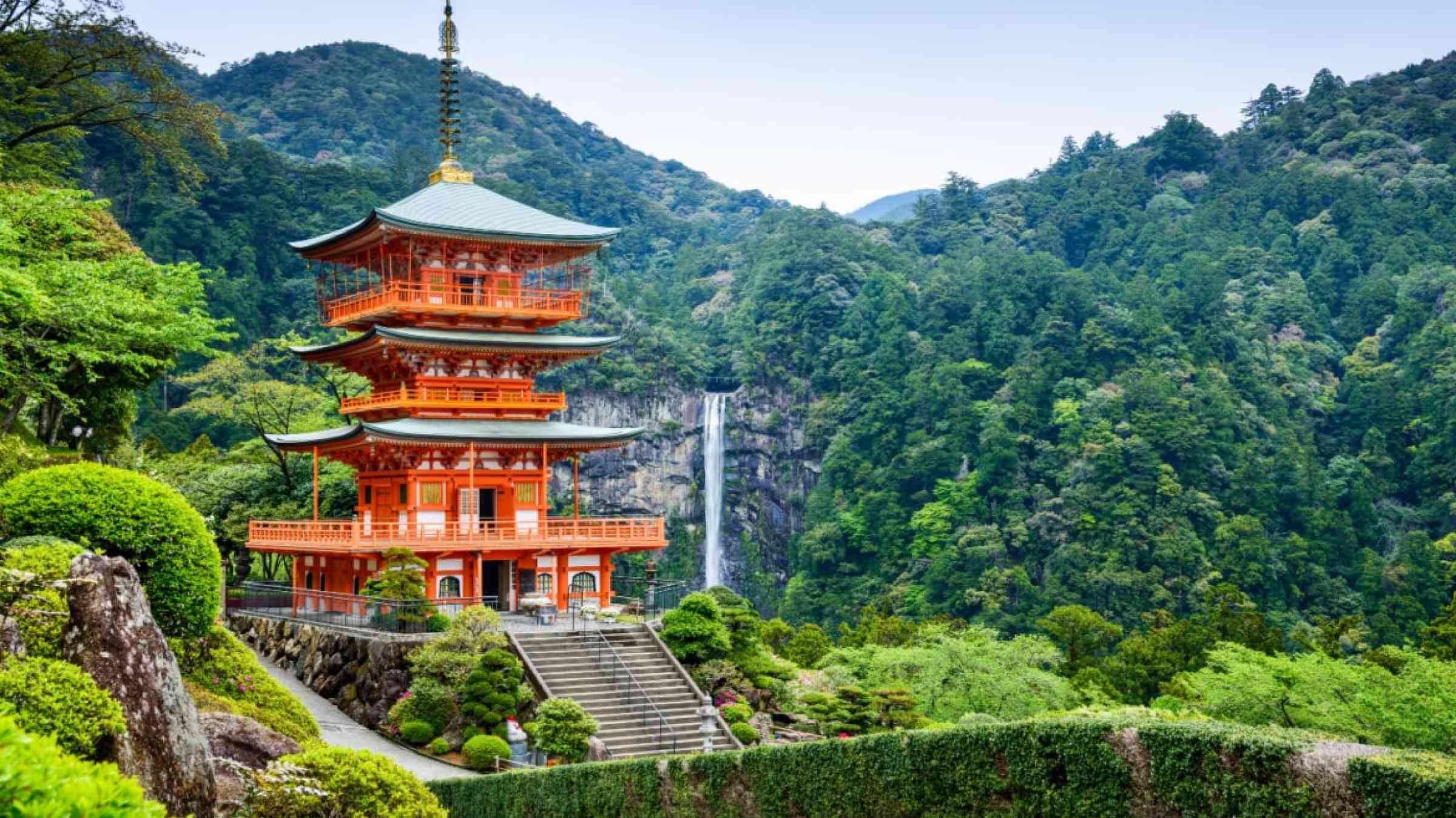 Temple in front of a waterfall in a forest in Japan.