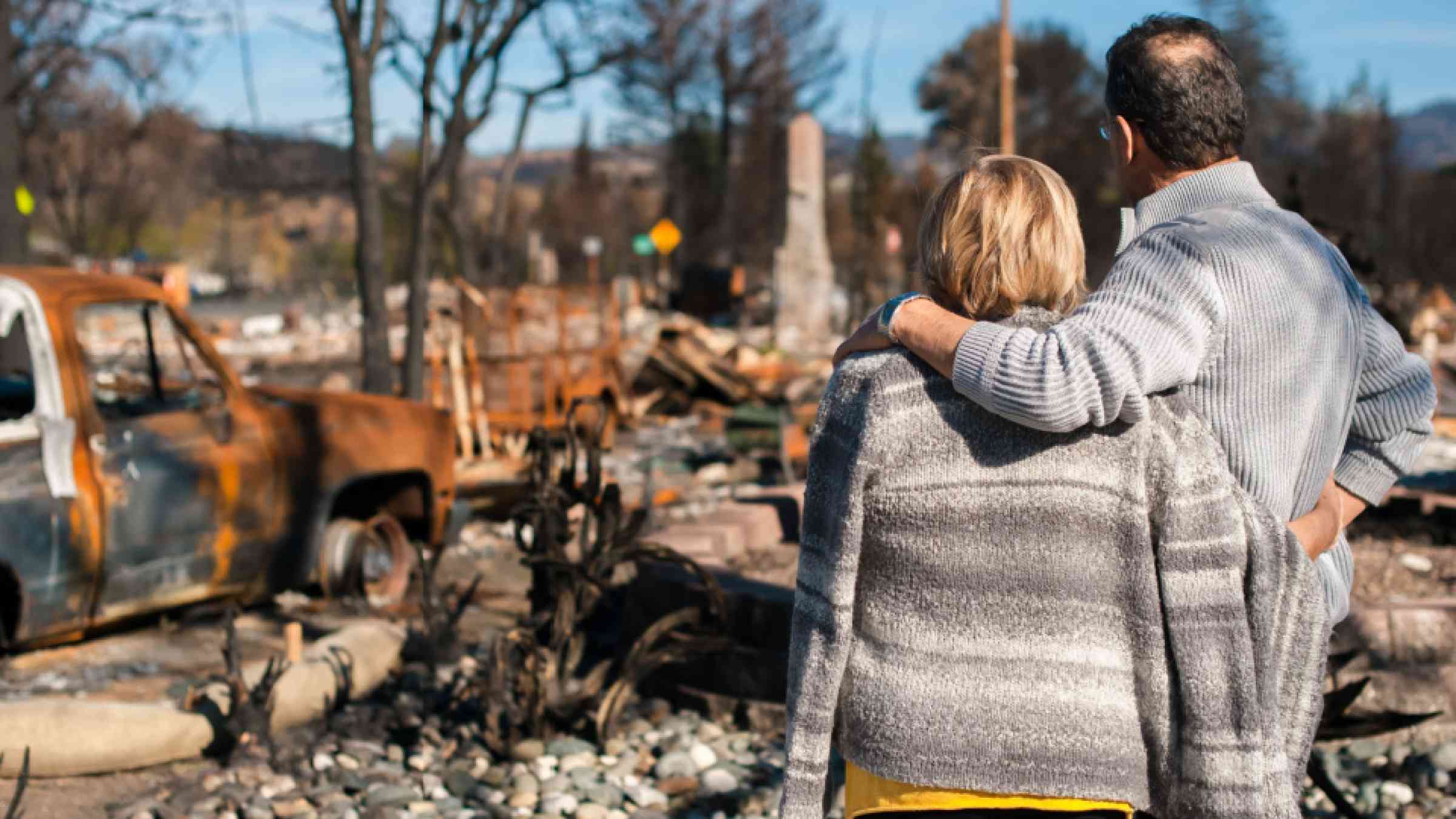 Woman and man look at the ruins of a home after the fire disaster.