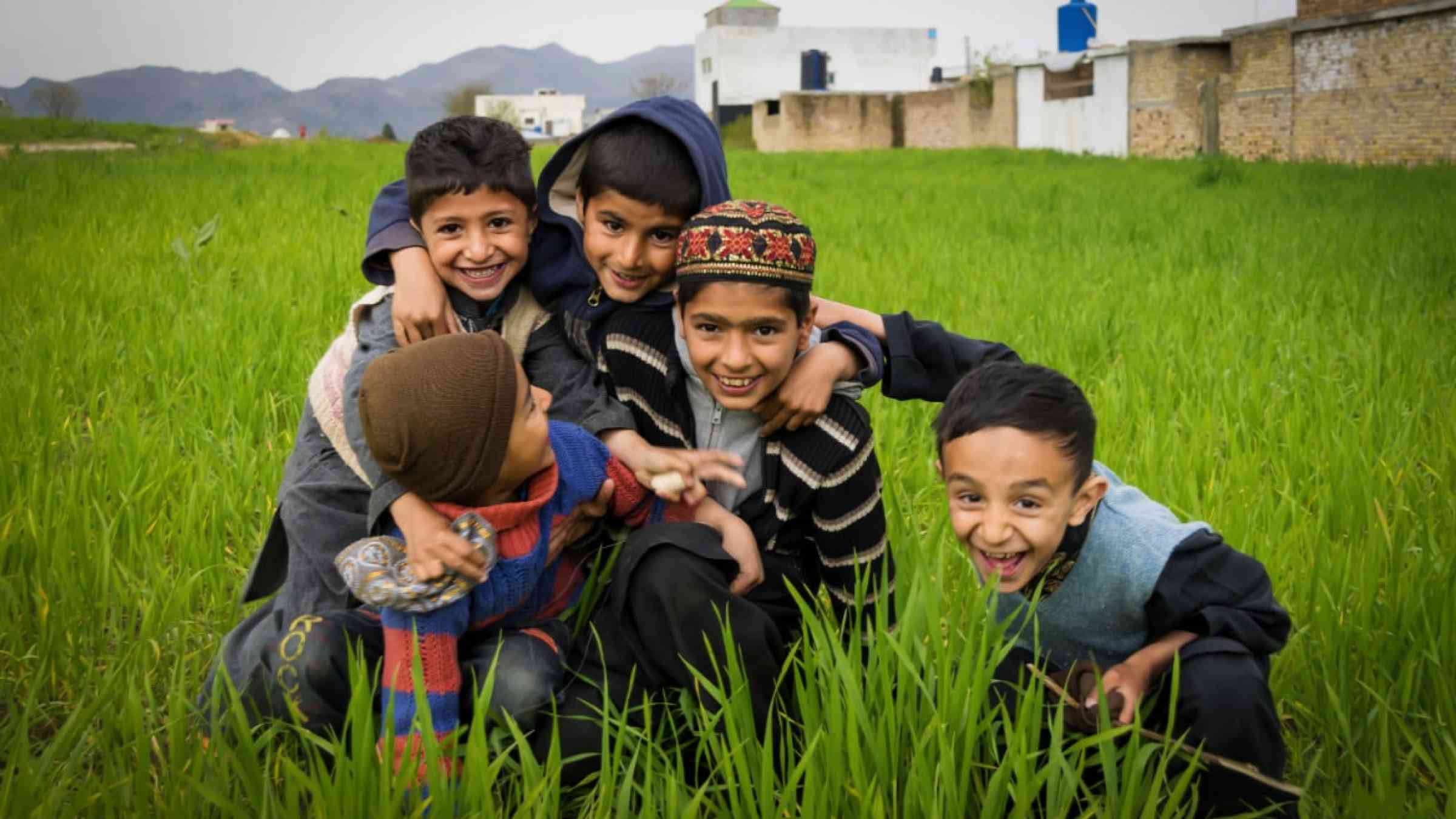 A group of five children from a village in Pakistan playing in the green field.
