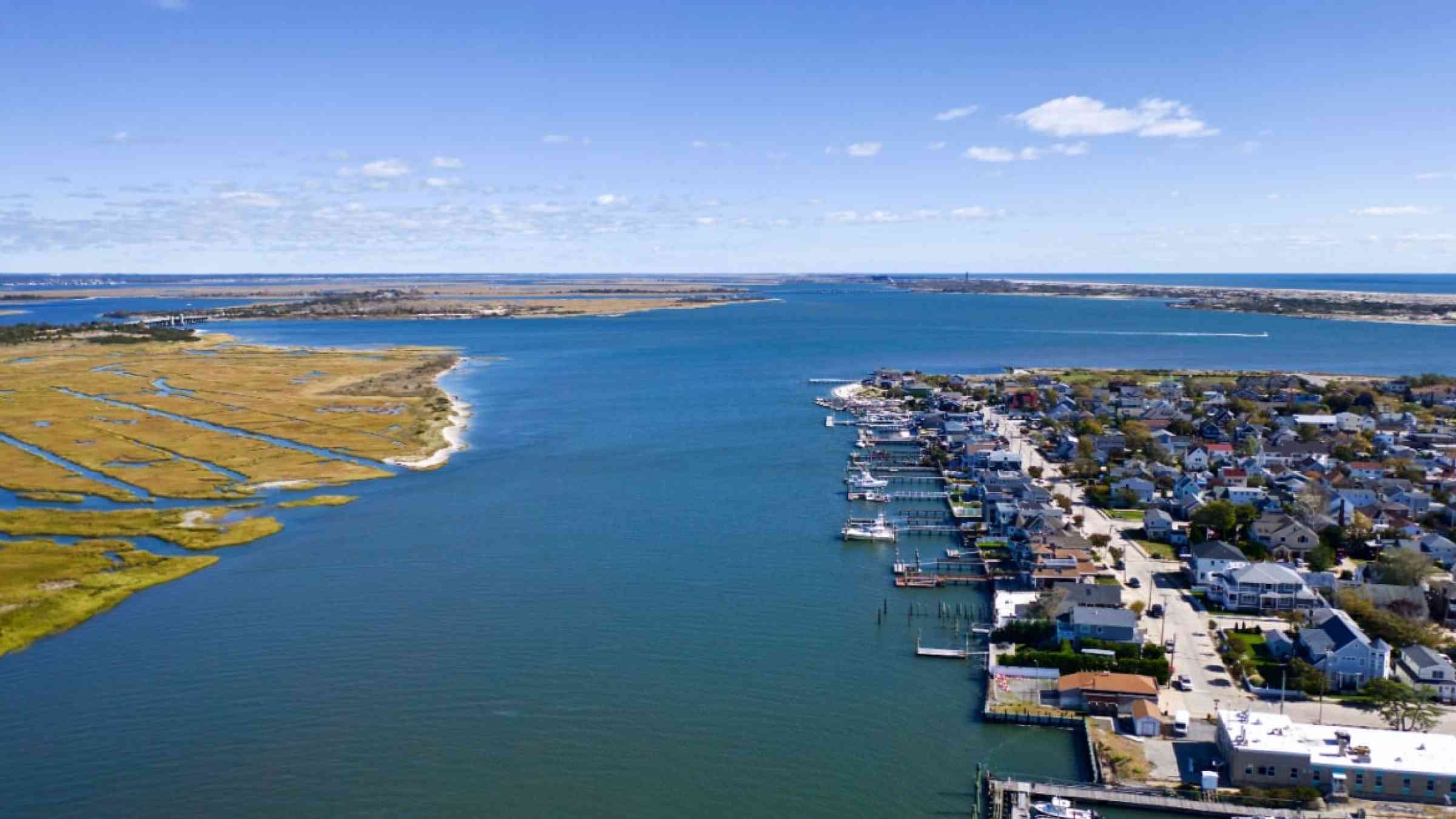 aerial shot over the marshlands, on a sunny morning at Point Lookout on Long Island, New York. Viewing the beautiful blue skies, a few clouds & some empty boats docked at the pier