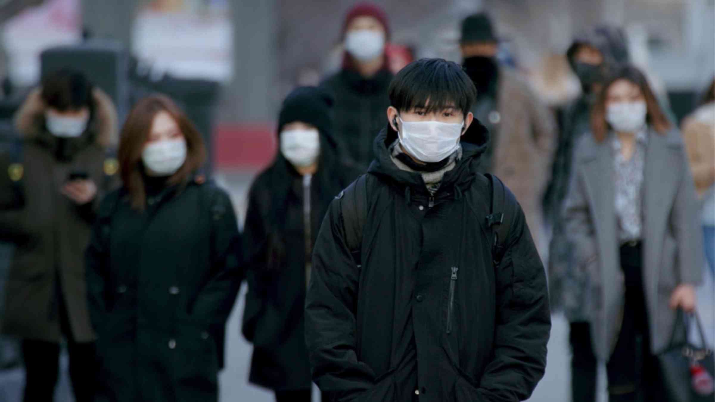 Man from South Korea walking through the streets waring a face mask for COVID-19 protection