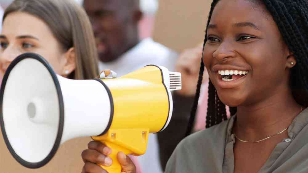 Cheerful young black lady leading international group of protestors