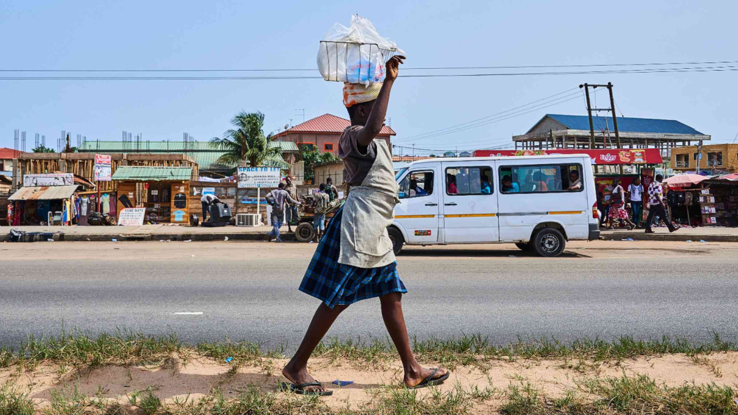 A woman who sells water on the street in Accra, Ghana, carries her load balanced on her head.