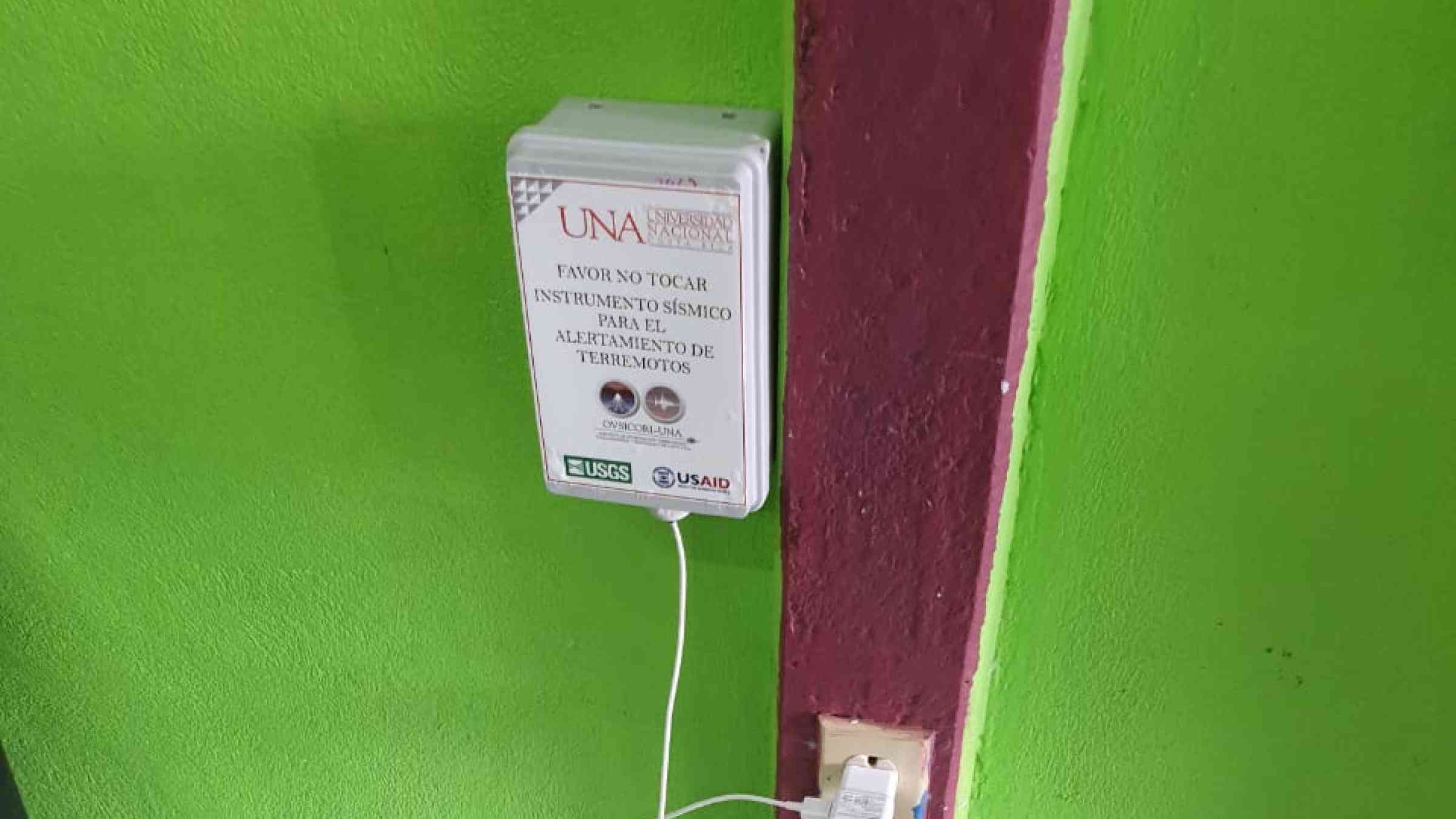 A smartphone for earthquake early warning boxed and plugged in to a wall in Costa Rica.