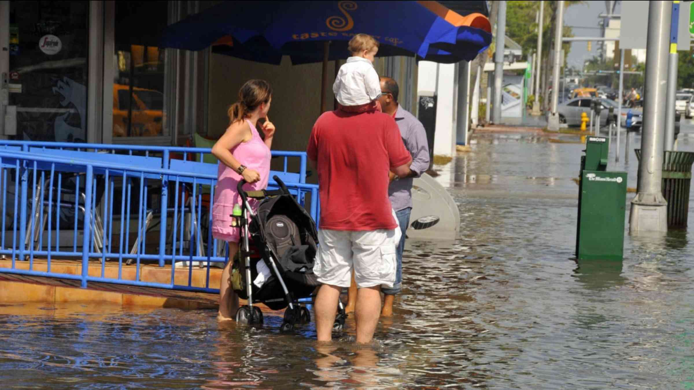 Family with a baby in the midst of a flooded street following Hurricane Sandy, in Miami (USA) in 2012.