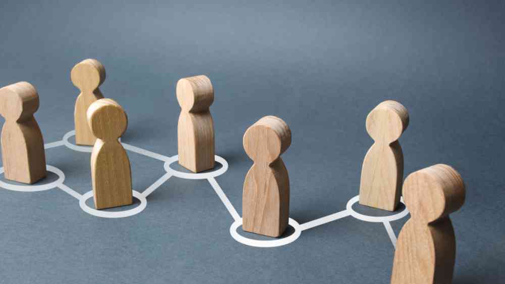 Chain of people wooden figurines connected by white lines.