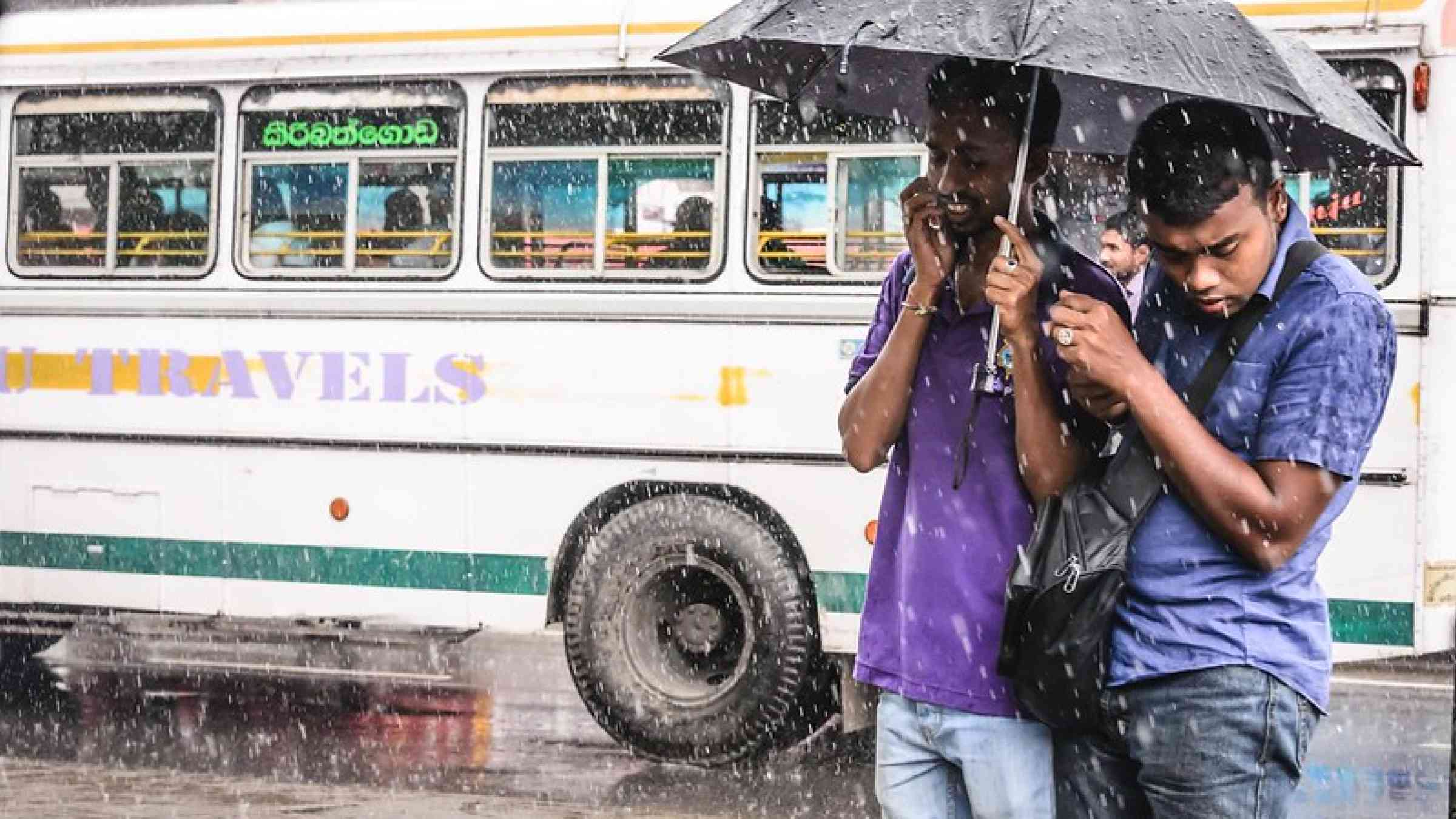 Young men in a downpour in Colombo, Sri Lanka