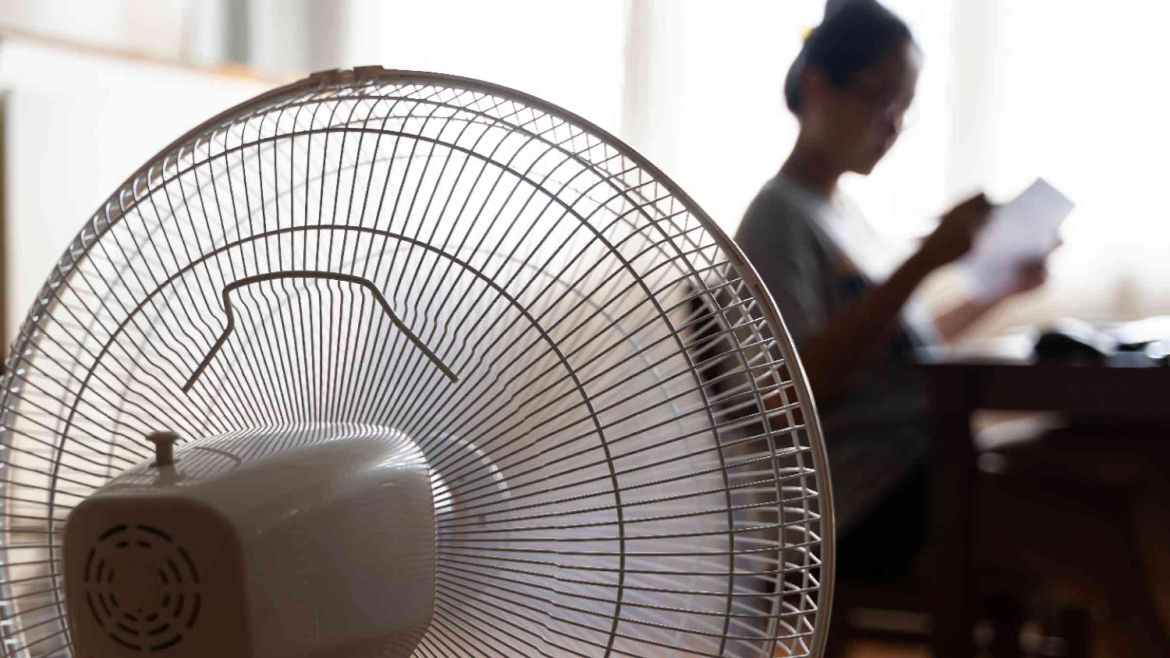 An electric fan cools down a resident inside her house