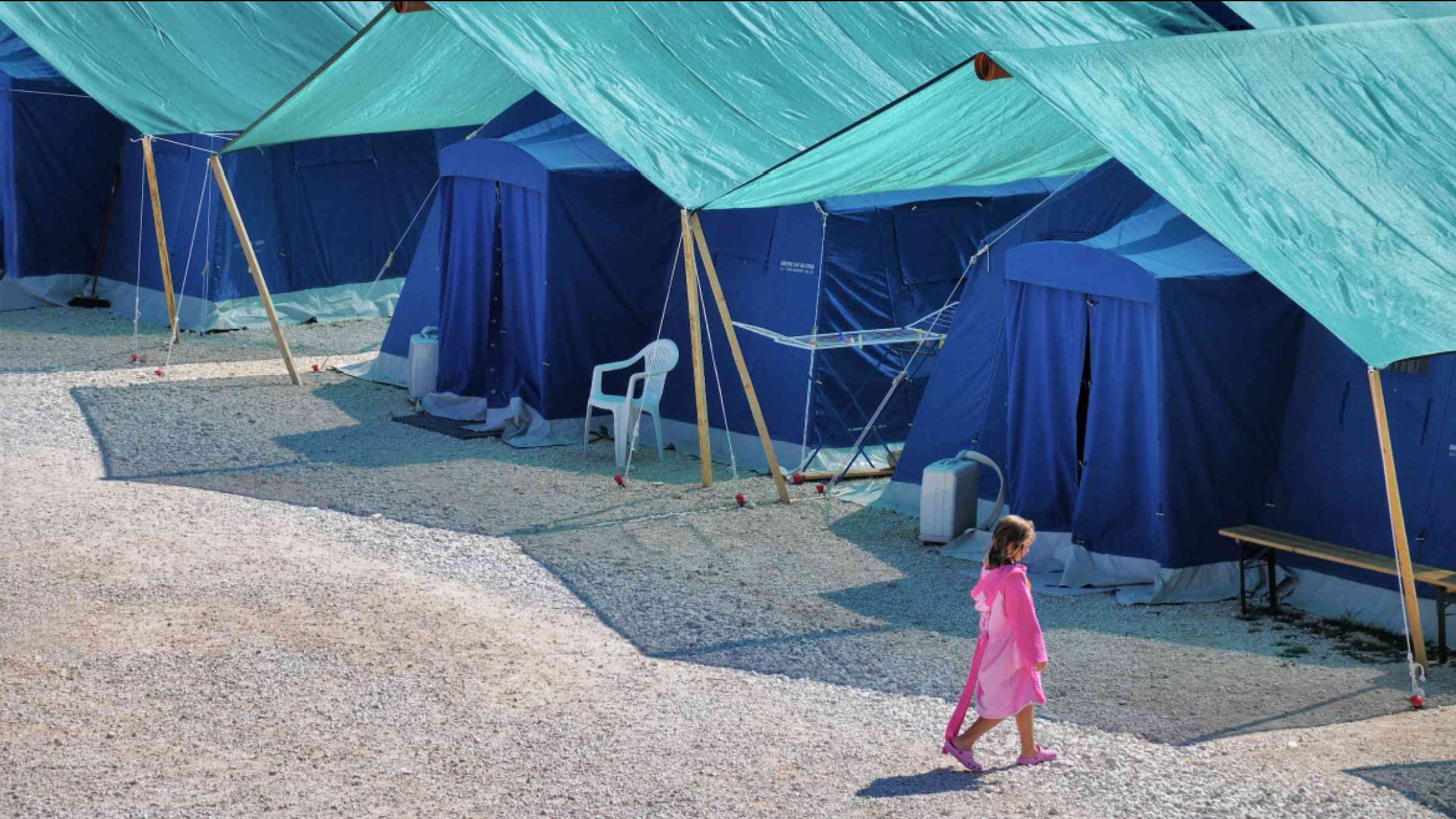 Earthquake refugees tent camp with a lonely child walking in Aquila Italy (August 2009)