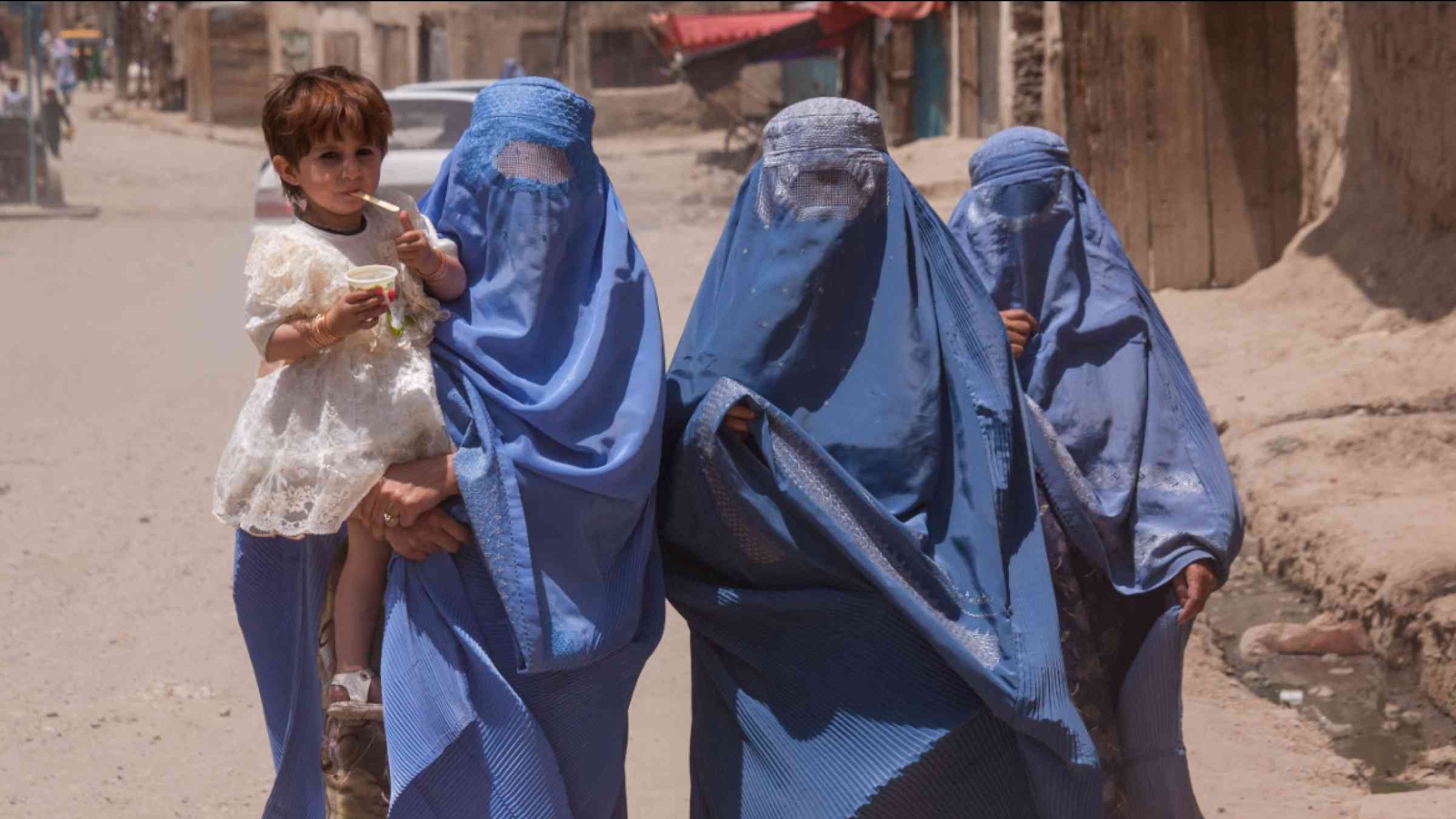 Women in burqas in Kabul walking with a child