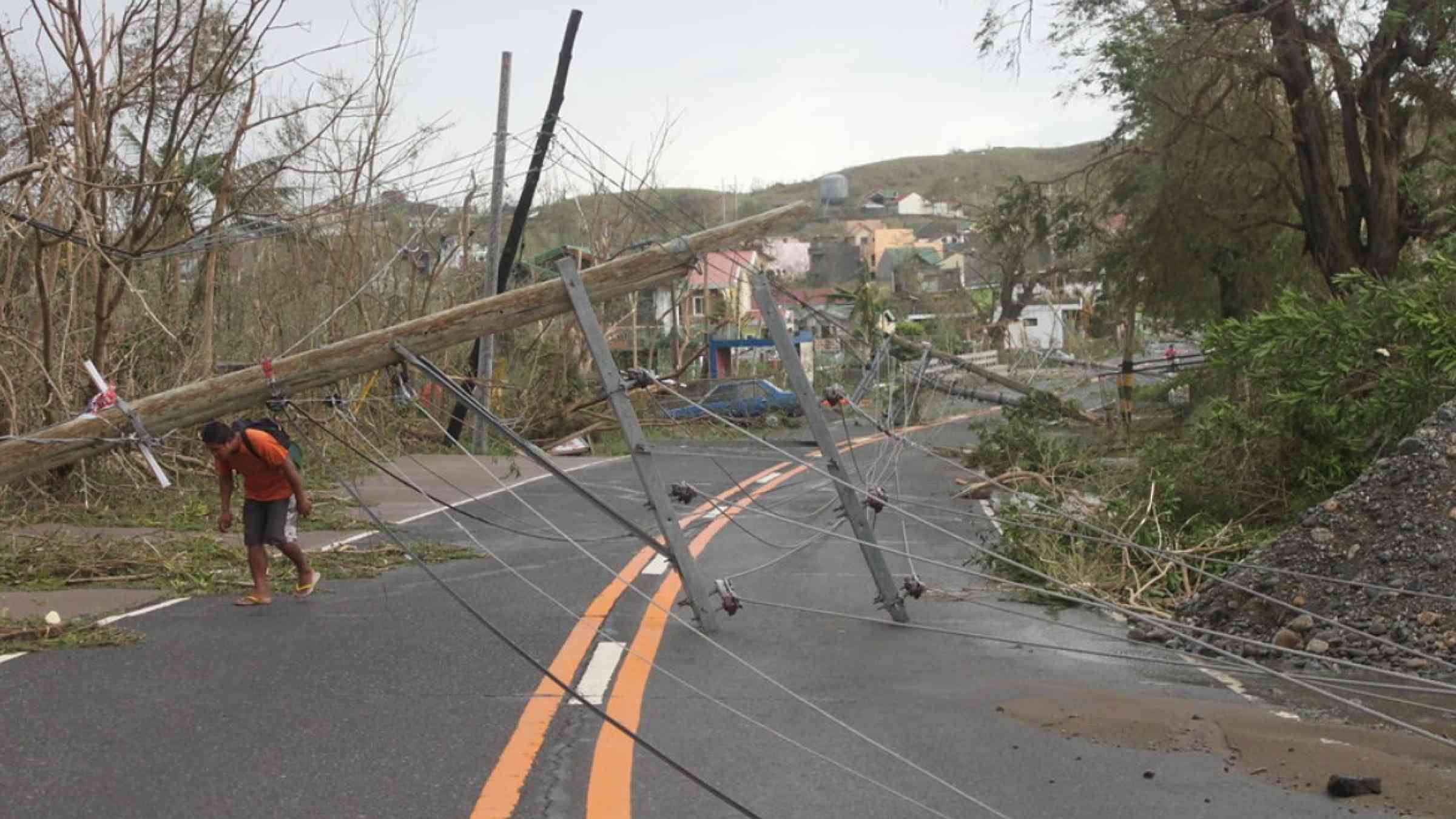 A villager crosses a road blocked by a toppled utility pole in the aftermath of Typhoon Haima