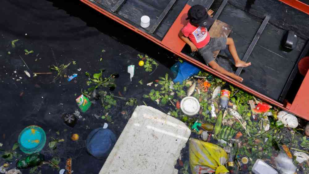 A child sits on a boat on a polluted river in Negro River, Amazon