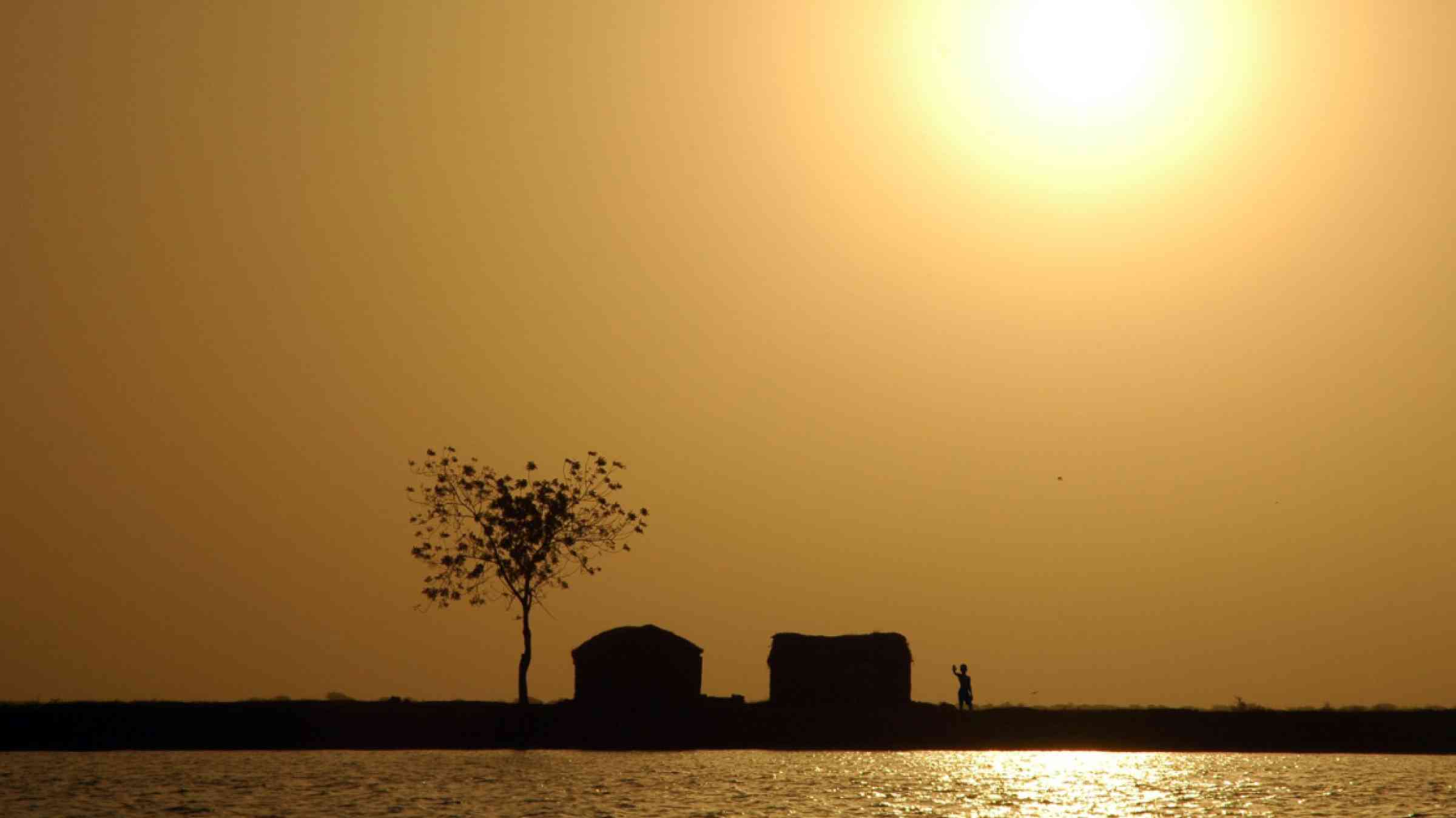 Sun over traditional West African homes along the Niger river shore