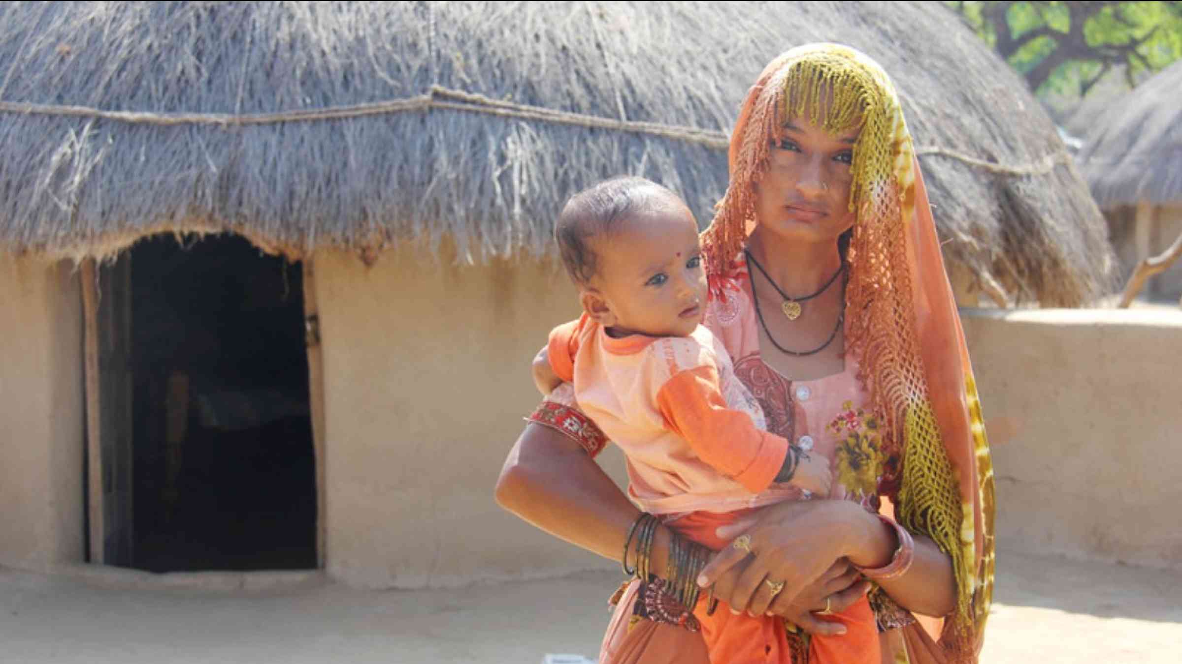 A mother-of-four from the Aban Jotar village, Sindh, Pakistan cradles her toddler while her husband works in the nearby fields, 