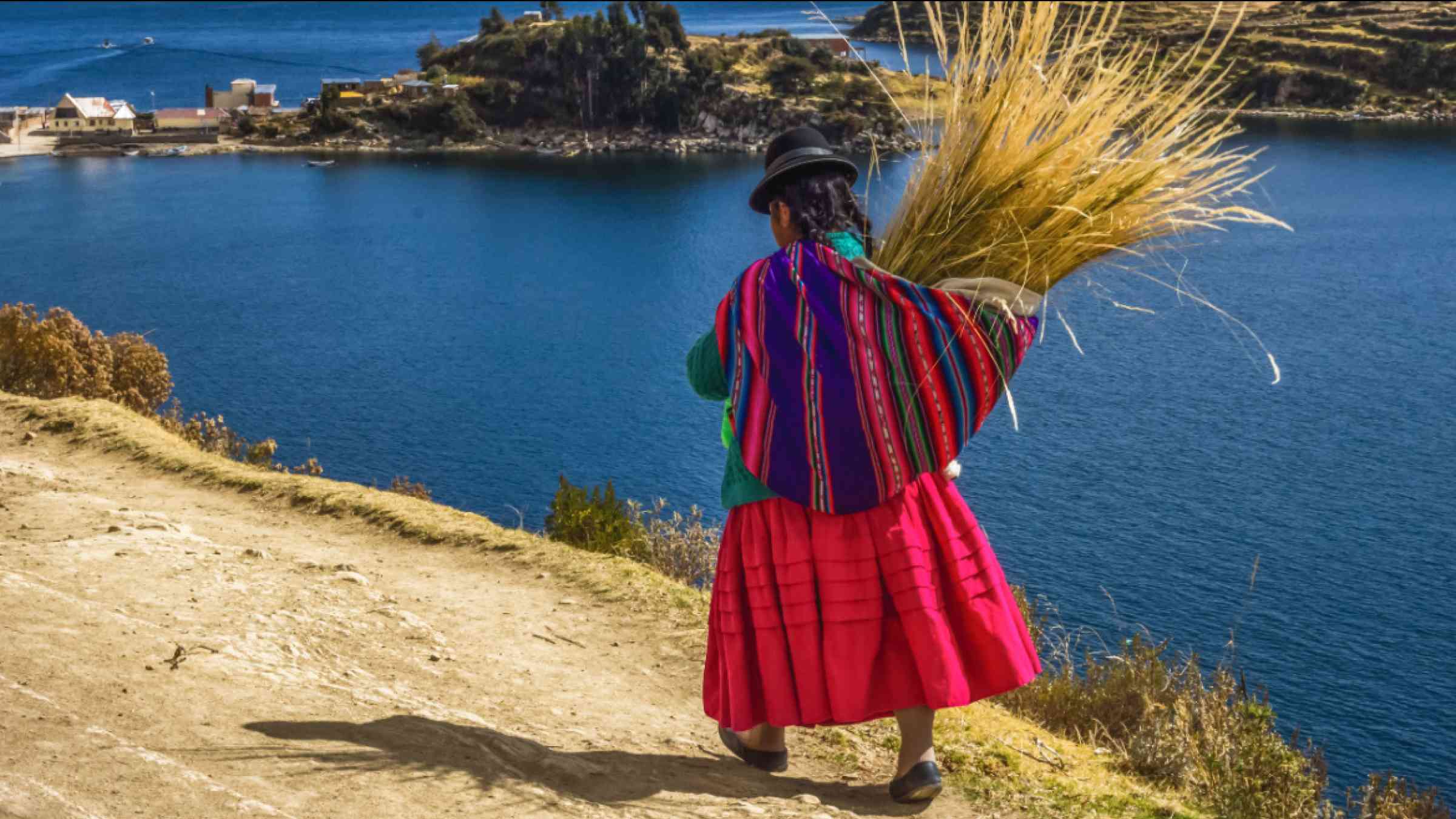 Traditional bolivian woman in traditional dress, walking trought the Sun island in lake Titicaca, Bolivia