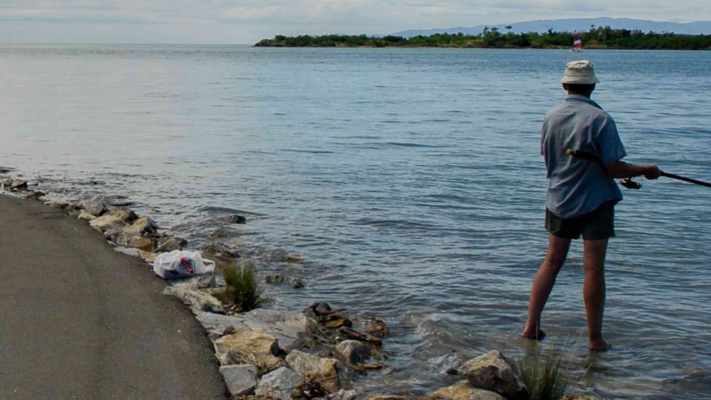 Fisherman standing alongside a flooded road