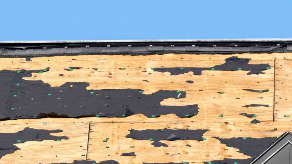 Damaged house roof with missing shingles after hurricane Ian in Florida.