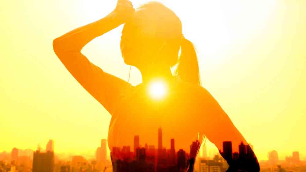 Double exposure portrait of young woman hand wiping sweat with summer heat wave background