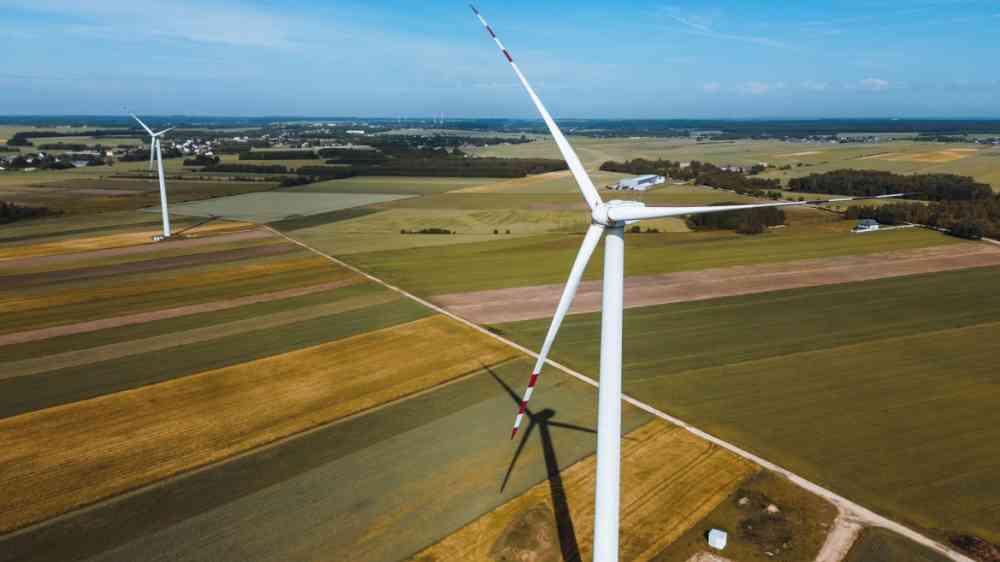 Wind turbine surrounded by agricultural fields and blue sky.