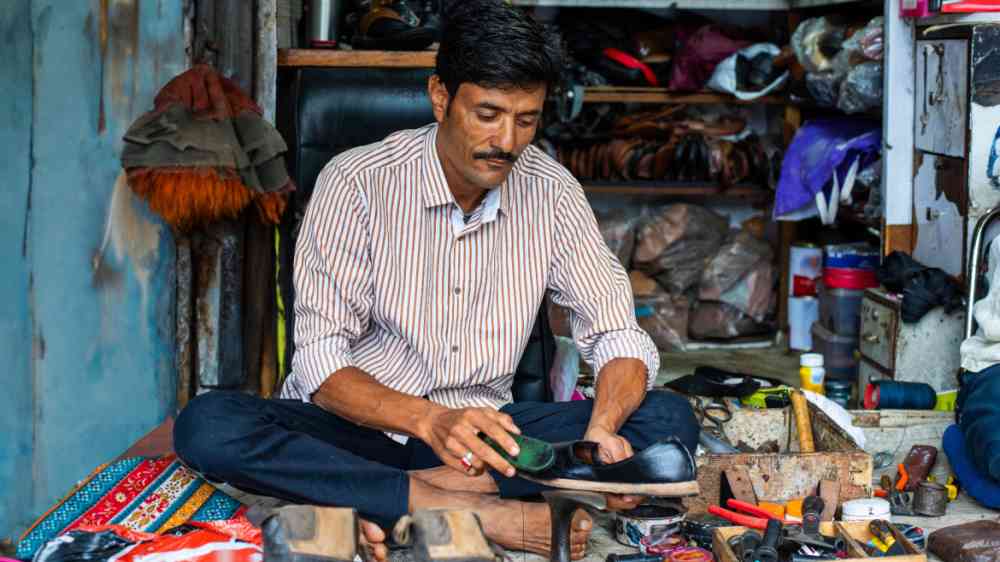 Indian man repairs shoes on the street.