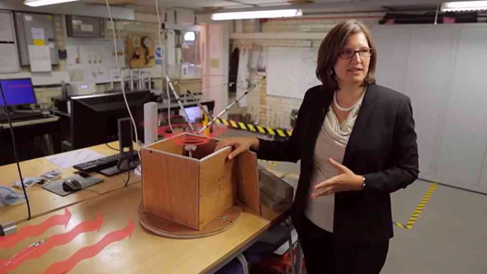 Professor Tiziana Rossetto, structural engineer and professor, stands beside a monitor box used in a tsunami simulator