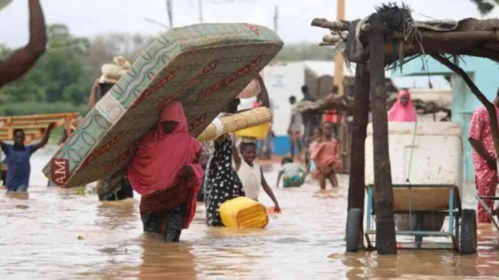 People carrying their belongings through a flooded street in Nigeria.