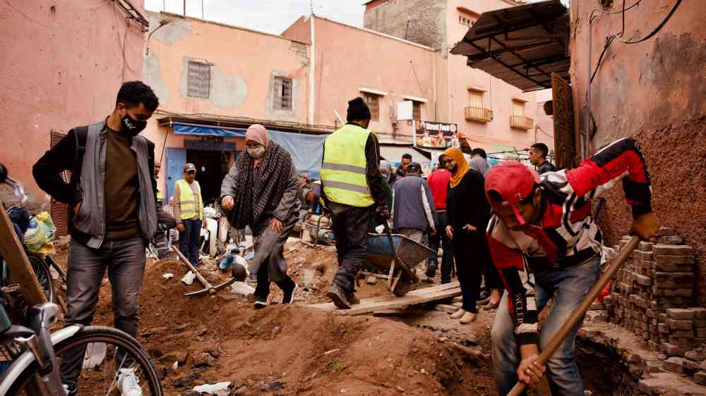 Volunteers engaging in road repairs in a busy Moroccan neighborhood.