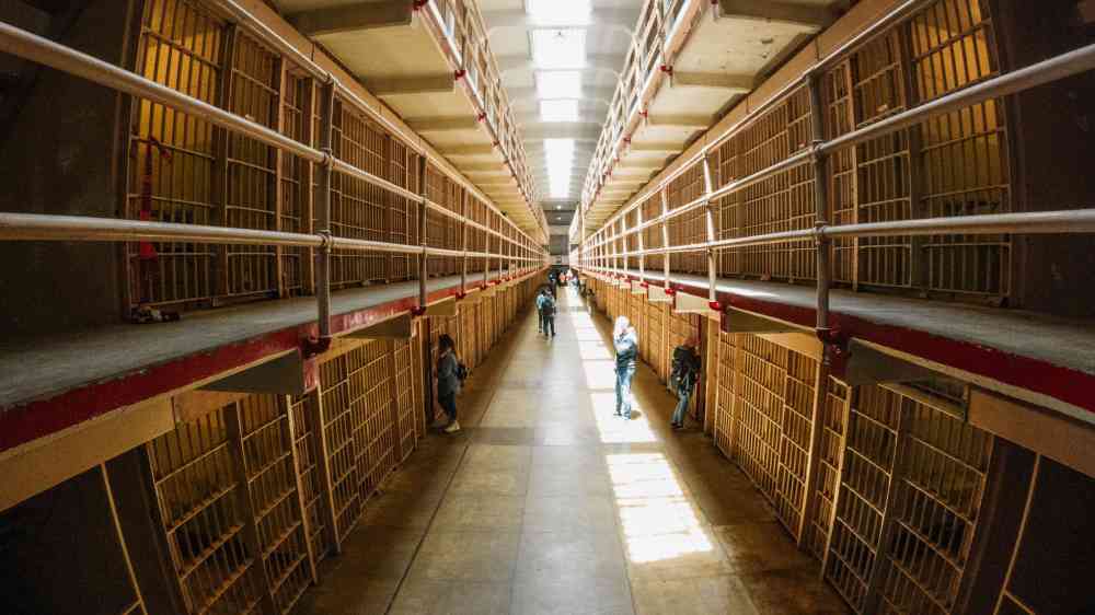Inside view of Alcatraz prison corridor filled with visitors exploring the historic site.