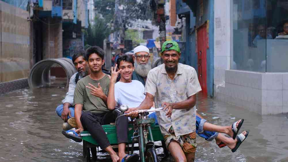 A flooded street with people riding a rickshaw through high water in an urban area