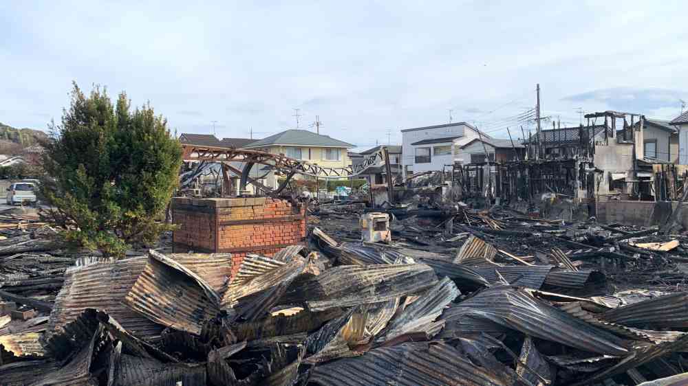 A scene showing destroyed buildings and debris after a large fire in an urban neighborhood.