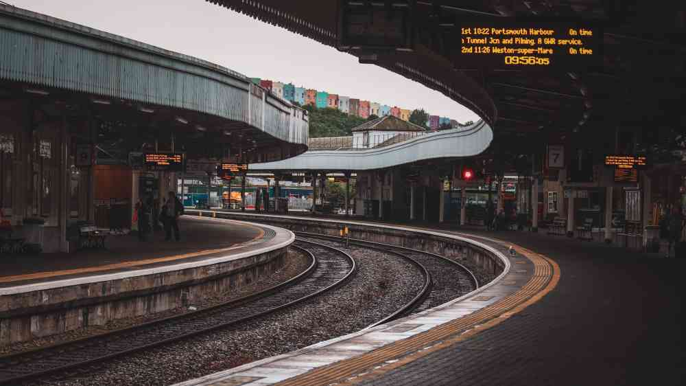 Urban train station with curved tracks and platform, featuring modern architecture.