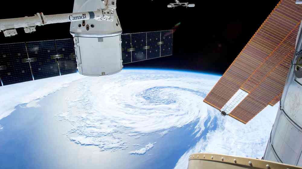 View of a hurricane on Earth as seen from a space station with solar panels and satellite modules