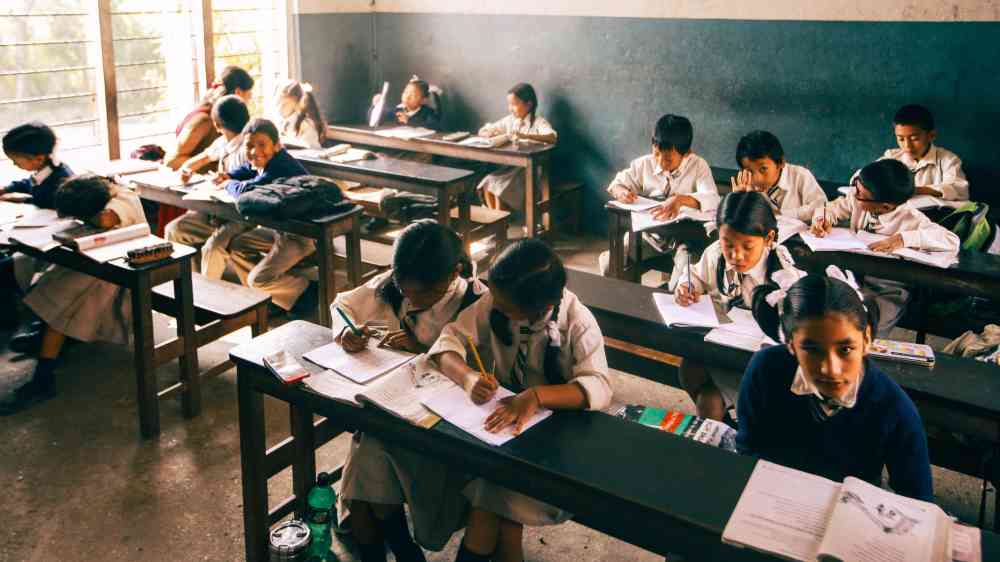 Elementary school children studying in a classroom, focusing intently on their work.