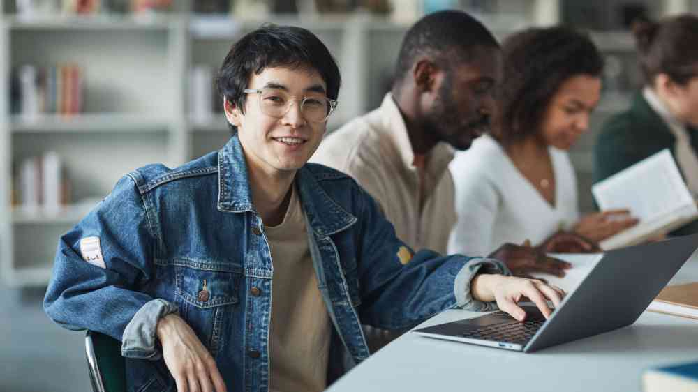 Students engaging in study session with laptops in a modern library.