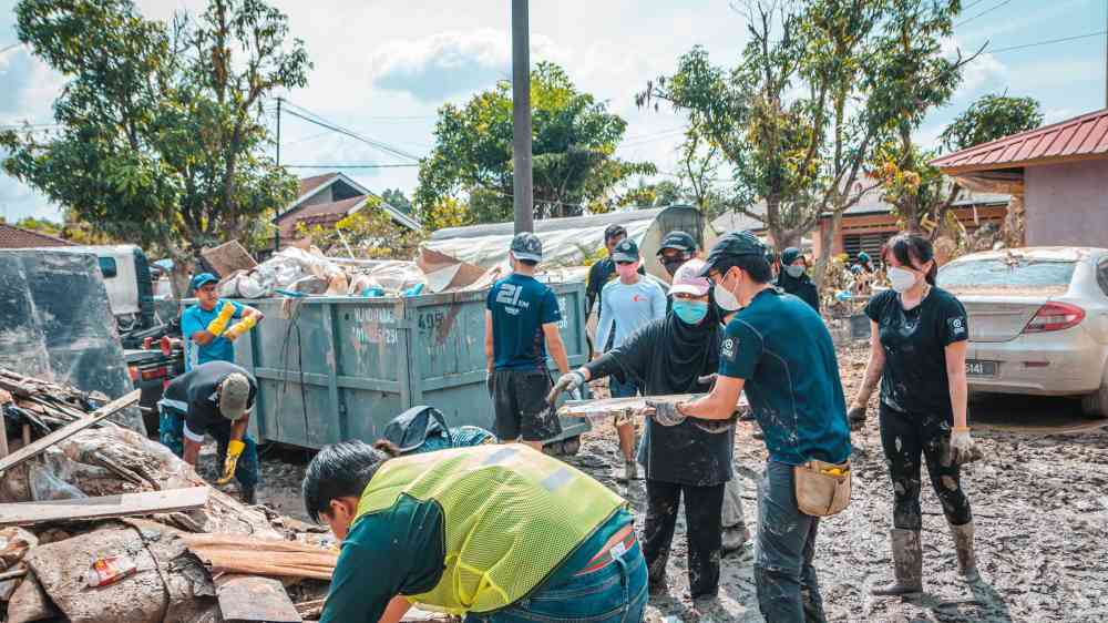 Volunteers work together to clean up debris after a disaster, showcasing community effort and teamwork.